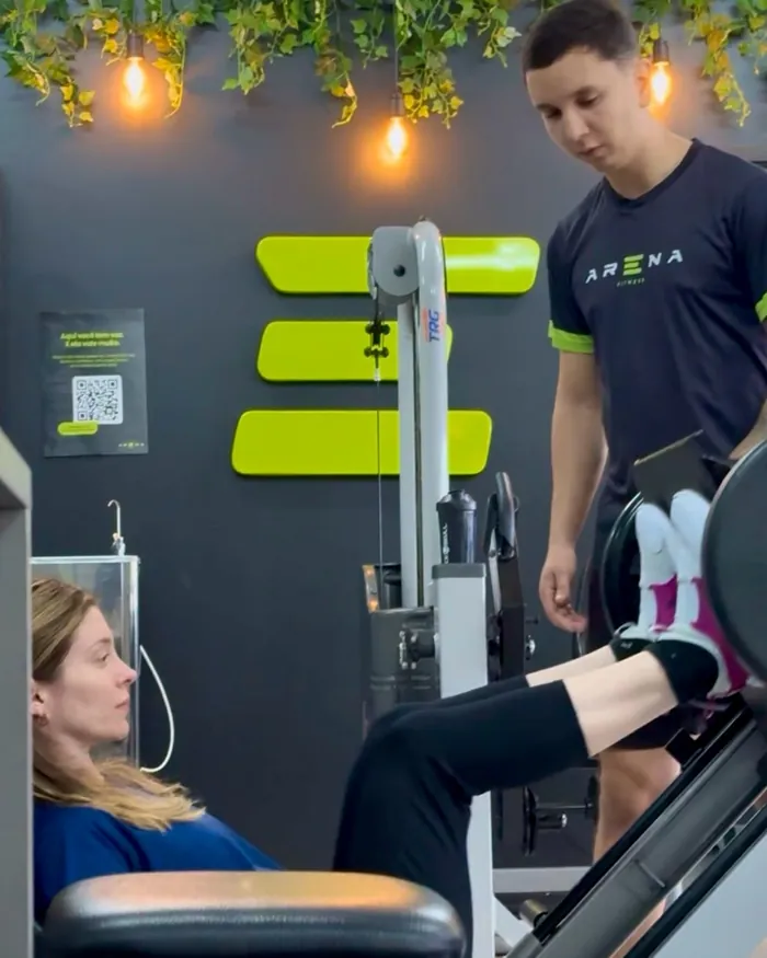 Professor do Arena Fitness acompanhando aluna no treino